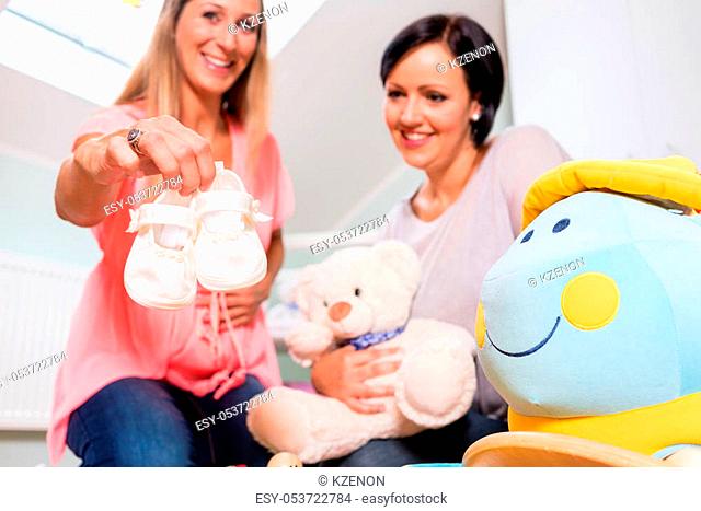 Heavily pregnant woman and friend arranging childs room
