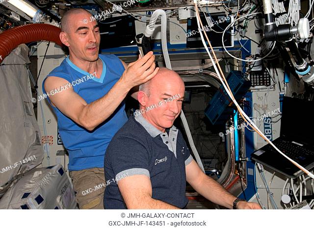 NASA astronaut Jeff Williams (right) gets a haircut aboard the International Space Station from Russian cosmonaut Anatoly Ivanishin (left