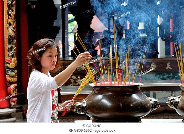 Buddhist worshipper placing incense sticks on joss stick pot, Taoist temple, Phuoc An Hoi Quan Pagoda, Ho Chi Minh City, Vietnam, Indochina, Southeast Asia