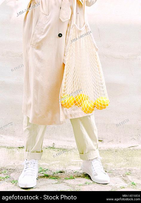 woman carries lemons in a shopping bag
