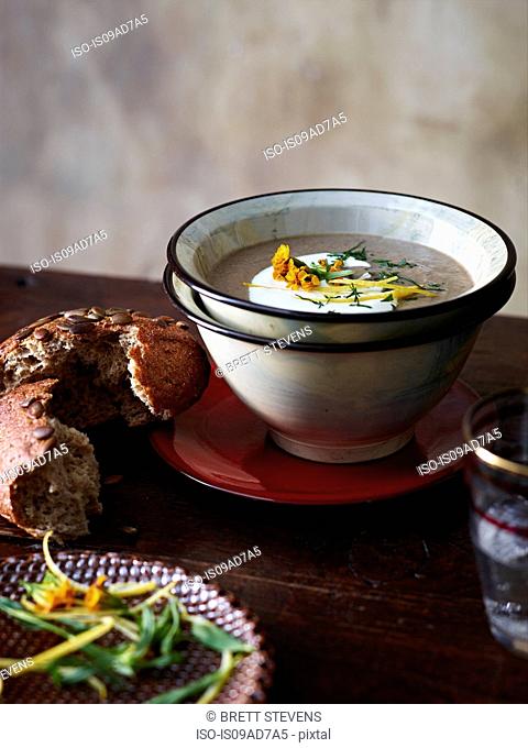 Table with bowl of mushroom and tarragon soup and brown bread