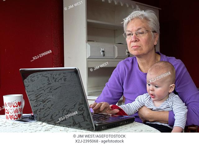 Denver, Colorado - Seven-month-old Adam Hjermstad Jr. tries to help his grandmother, Susan Newell, 66, as she works on a computer