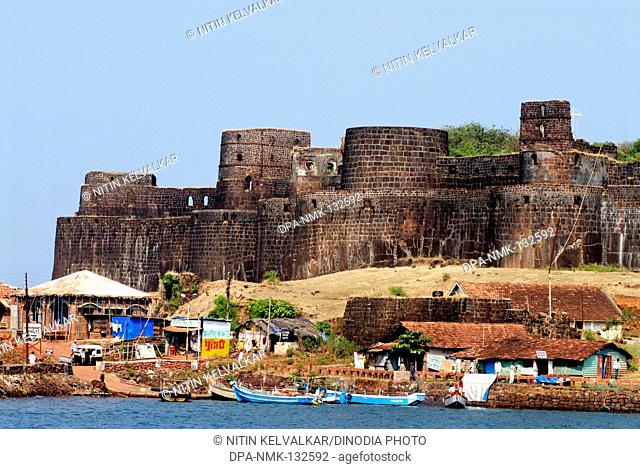 Strong bastions and rampart of Vijaydurg ; fort constructed by king Bhoj in the year 1195 to 1205 ; surrounded by Arabian sea and village houses ; Konkan coast...