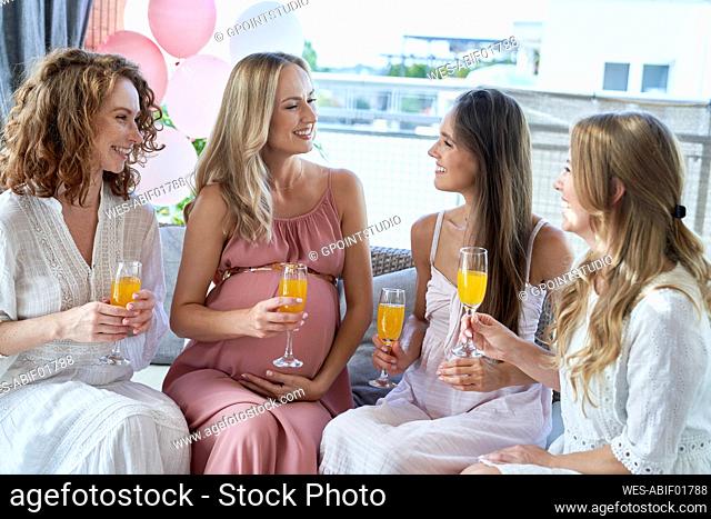 Smiling pregnant woman enjoying with friends at baby shower
