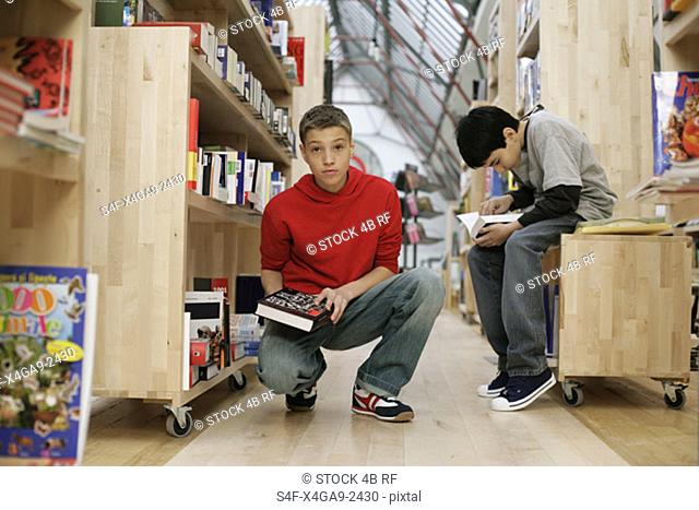 Two boys reading inside a library, fully-released