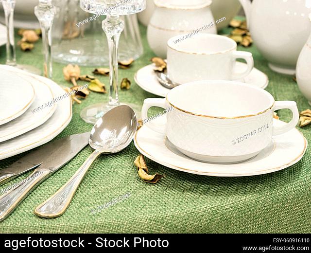 Set of new dishes on table with green tablecloth in restaurant