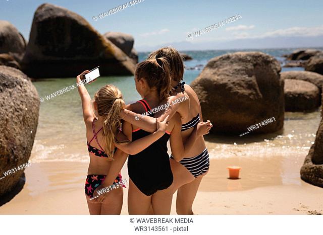 Rear view of siblings taking selfie with mobile phone