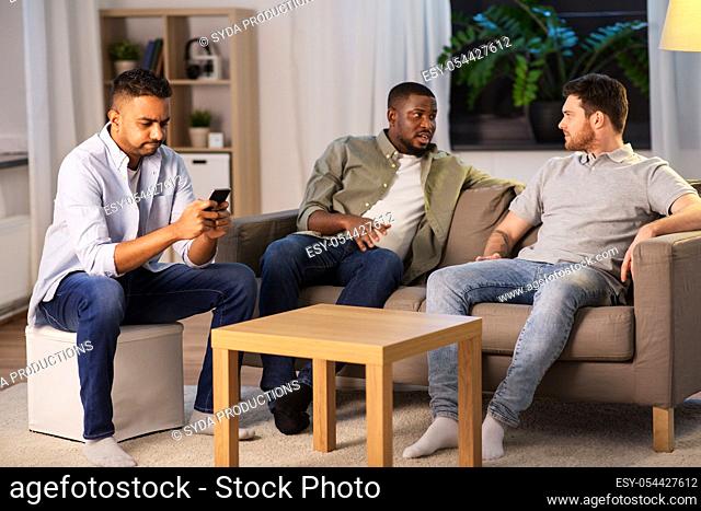 man using smartphone while friends talking at home