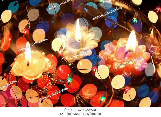 An abstract image of floating candles behind a wire mesh of colorful lights, during Diwali festival in India