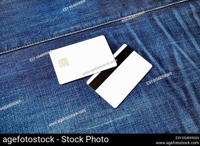 Two bank plastic bank cards on denim background. White credit cards. Front and back view