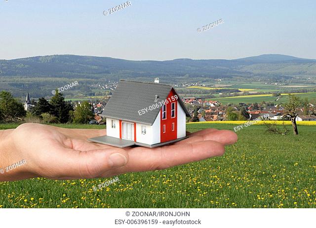 Hand with house in front of landscape