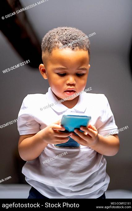 Cute boy using smart phone at home