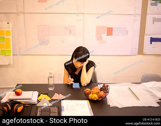 Female architect using smart phone in office