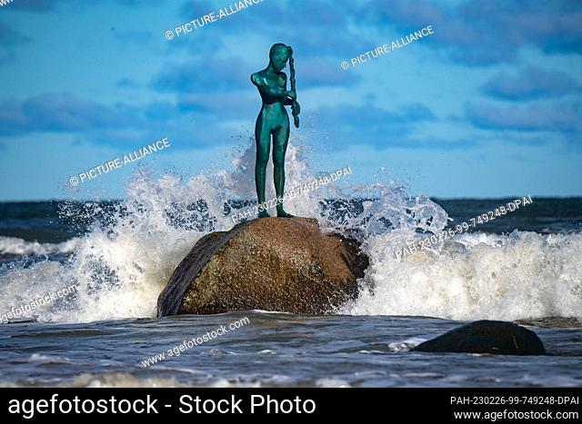 26 February 2023, Mecklenburg-Western Pomerania, Sellin: Waves crash on the beach of the island of Rügen. The bronze sculpture ""Kaysa"" was created in 2014 by...