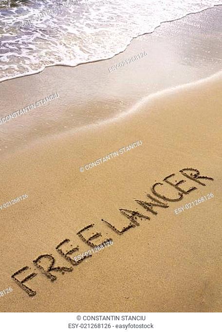 Word FREELANCER written in sand, on a beautiful beach