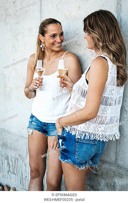 Two best friends drinking champagne outdoors