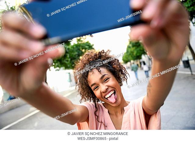 Carefree young woman taking a selfie in the city