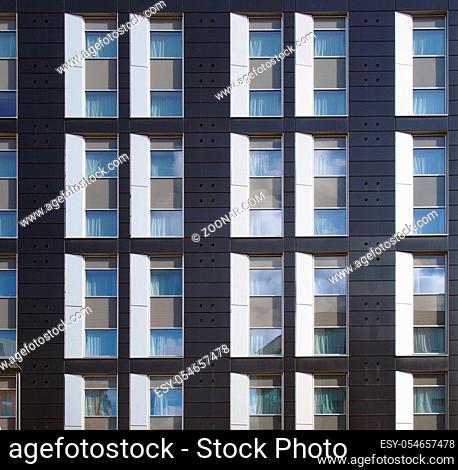facade of a large black and white modern commercial building with repeating windows and geometric panels