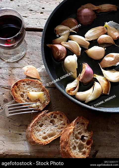 Pan-fried cloves of garlic with baguette bread