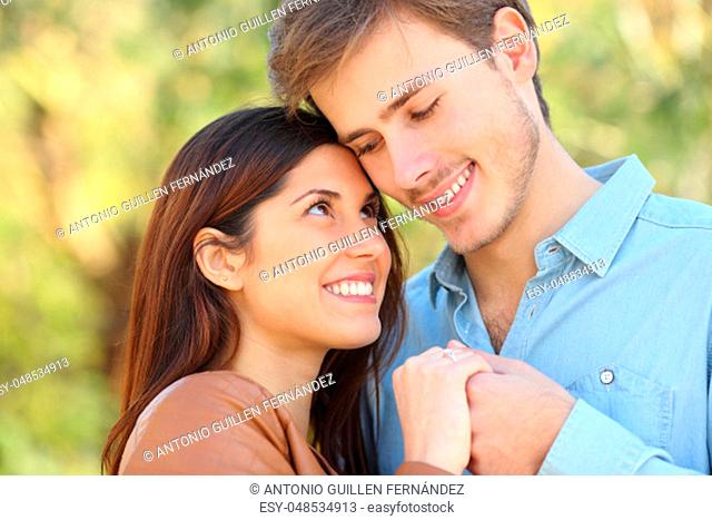 Happy couple in love looking each other holding hands standing in a park