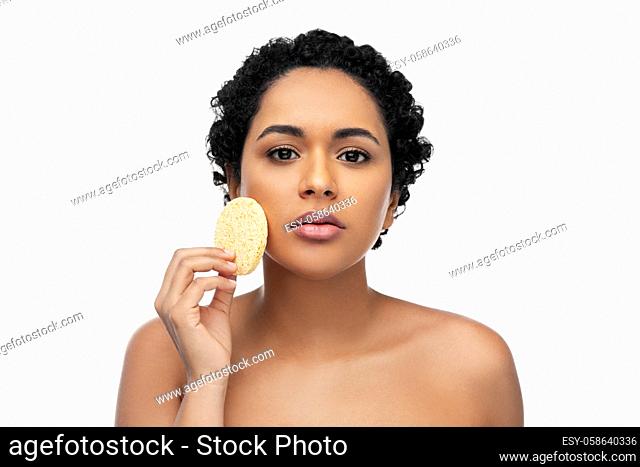 young woman cleaning face with exfoliating sponge
