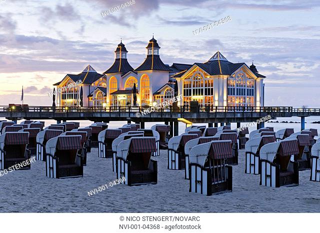 Beach chairs on the sandy beach of the Baltic resort Sellin, in the back the historic pier with restaurant, Ruegen island, Mecklenburg-Western Pomerania