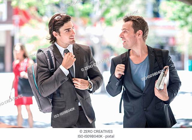 Two businessmen walking and talking in city