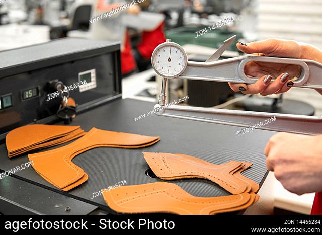 Woman hands use Leather thickness gauge on with a natural brown leather. Preparing of the raw materials for manufacture of bags, shoes, clothing and accessories