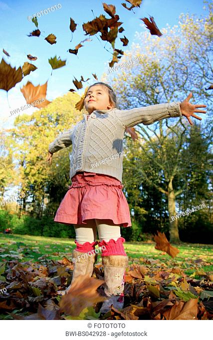 girl tossing autumn foliage