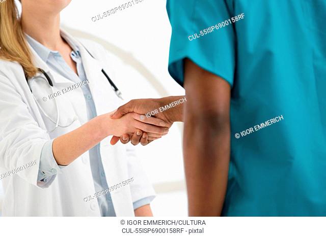 Two doctors shaking hands, mid section