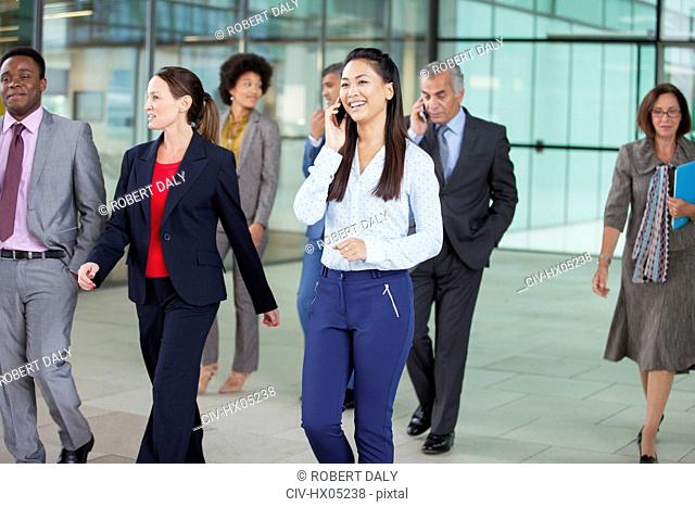Smiling businesswoman talking on cell phone and walking