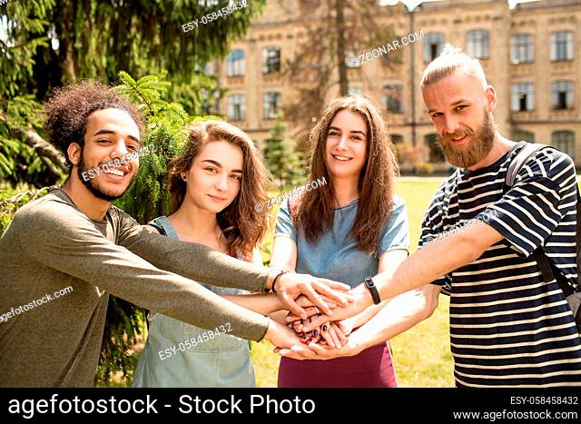 Happy young students holding hands together. Young people smiling standing in the park