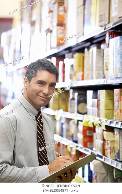 Hispanic grocery store manager holding clipboard