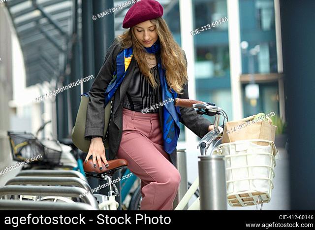 Young woman getting on bicycle