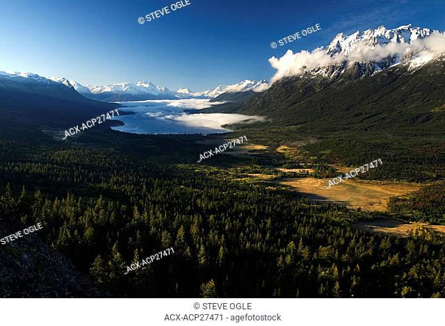 Tatlayoko Lake, showing farm fields, clouds and the Coast Mountains, British Columbia, Canada