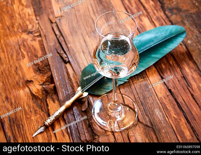 Grappa in a small glas on old wooden table, selective focus