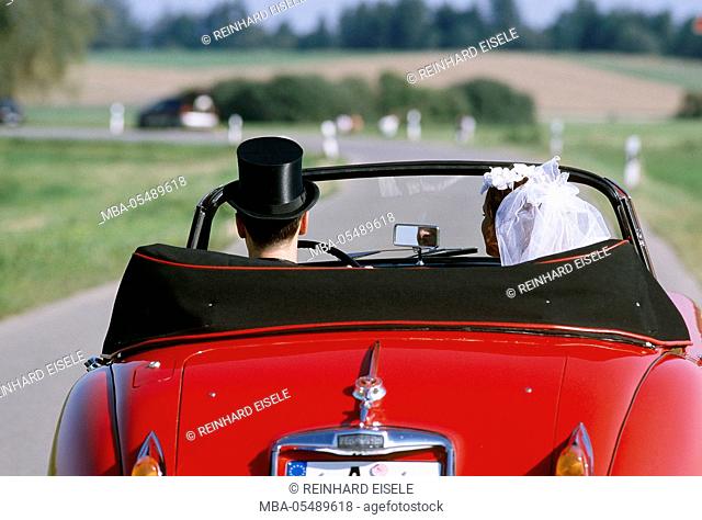 Wedding couple in red cabriolet
