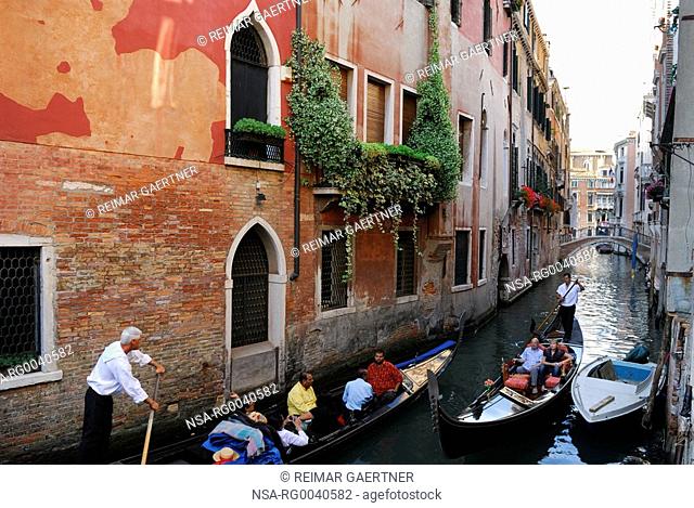 Two gondoliers negotiating a narrow canal in Venice
