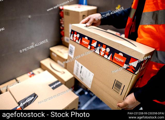07 December 2023, Lower Saxony, Großenkneten: An employee places a parcel on a trolley ready for dispatch in the outgoing goods department at Amazon's new...