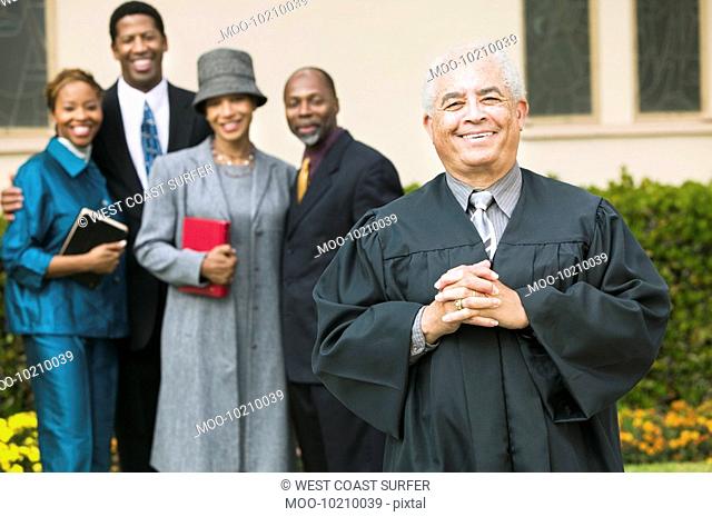 Smiling Preacher in church garden worshipers in background portrait