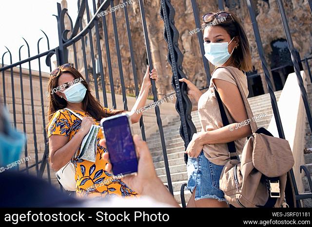 Man taking photo of women wearing face mask standing by gate against Sagrada Familia at Barcelona, Catalonia, Spain