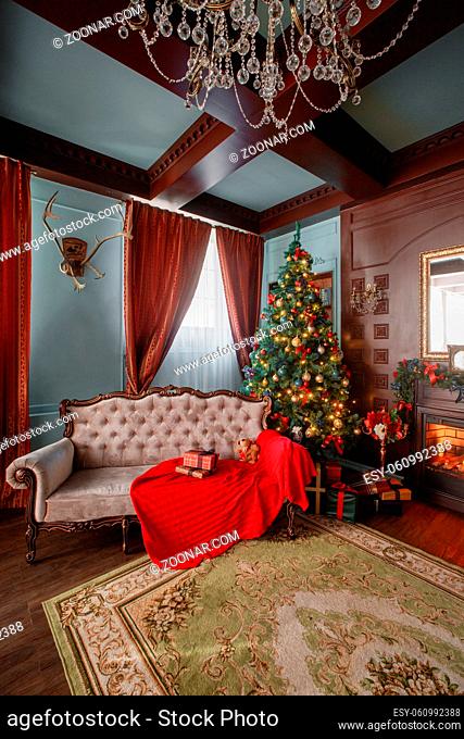 Christmas Eve by candlelight. classic apartments with a white fireplace, decorated tree, sofa, large windows and chandelier