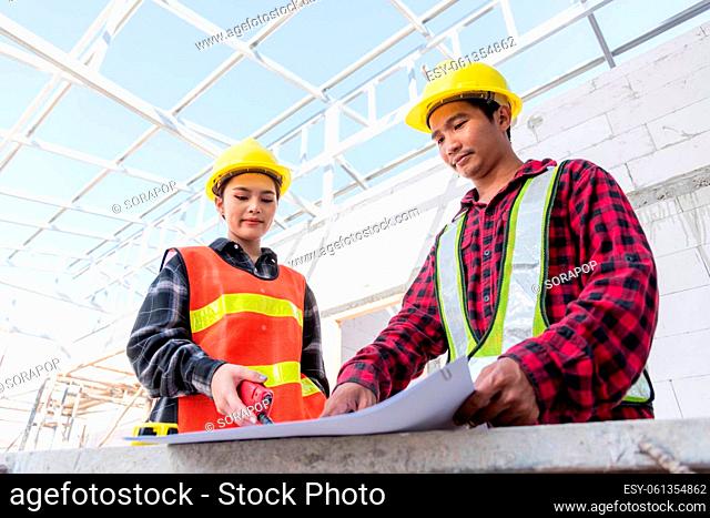 Architect and client discussing help create plan with blueprint of the building at construction site floor. Asian engineer foreman worker man and woman meeting...