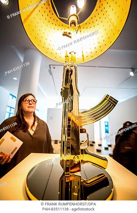 A museum employee stands next to a lamp by designer Philippe Starck in the shape of a machine gun during the press preview of the exhibition 'Under Arms: Fire...