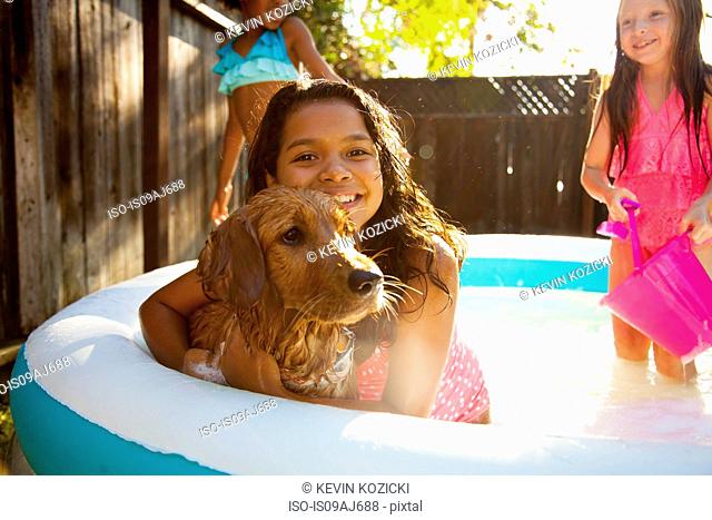 Three girls and a dog in garden paddling pool
