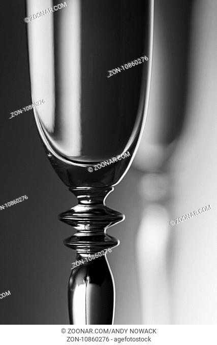 Oberer Teil eines Sektglases vor einem Helligkeits verlaufenden Hintergrund; monochrom