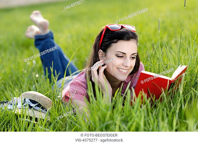 woman lying with book in meadow - , 05/04/2014