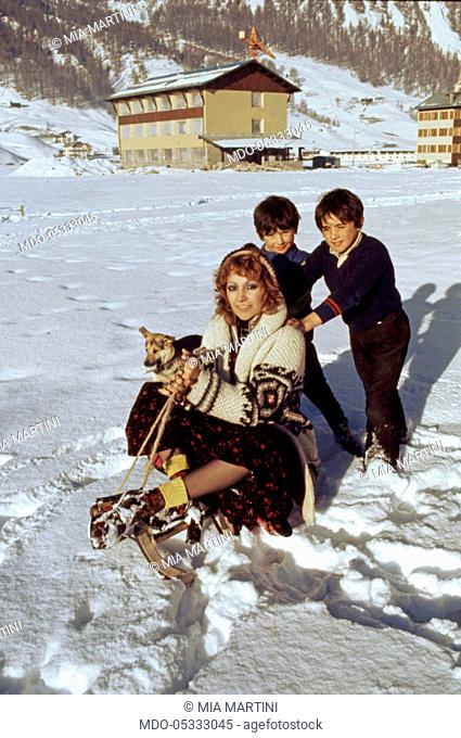 The singer Mia Martini (Domenica Rita Adriana Bertè) playing in the snow with two children. Livigno, Italy. 1973