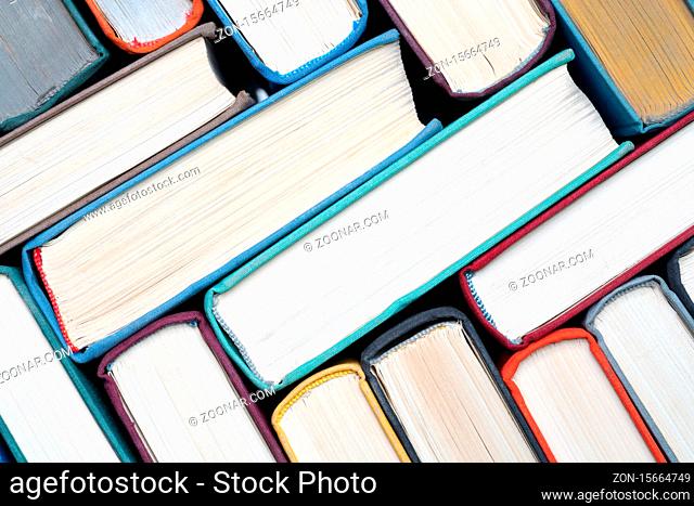 Stack of hardcover books on bookshelf. Close-up view of vintage hardback books as background