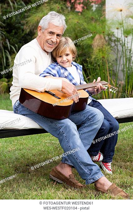 Grandfather and grandson with guitar outdoors